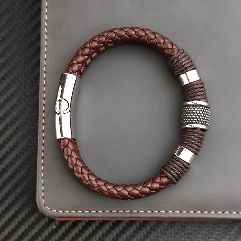 Brown braided leather bracelet with silver clasp on a gray textured surface
