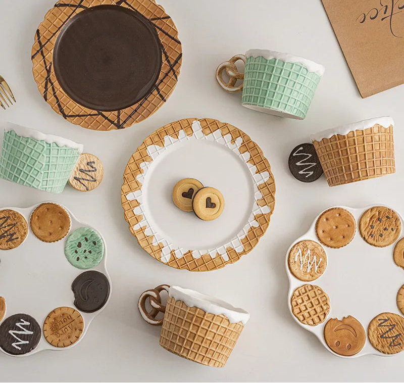Assorted ceramic plates, cups, and cookies on a white surface 