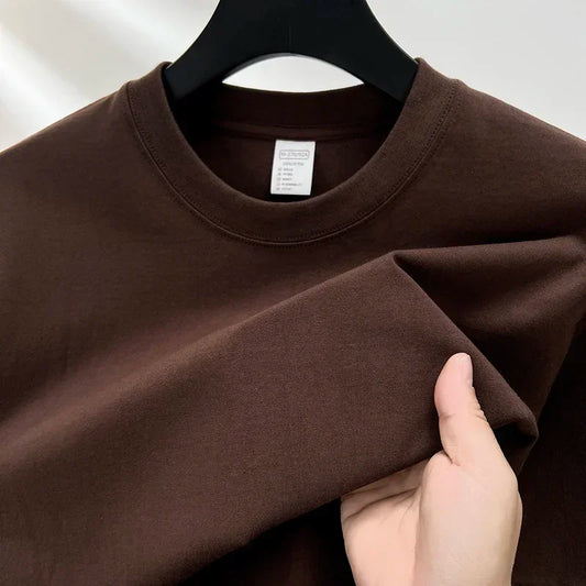 Brown sweatshirt on a hanger with a hand holding it, against a white background