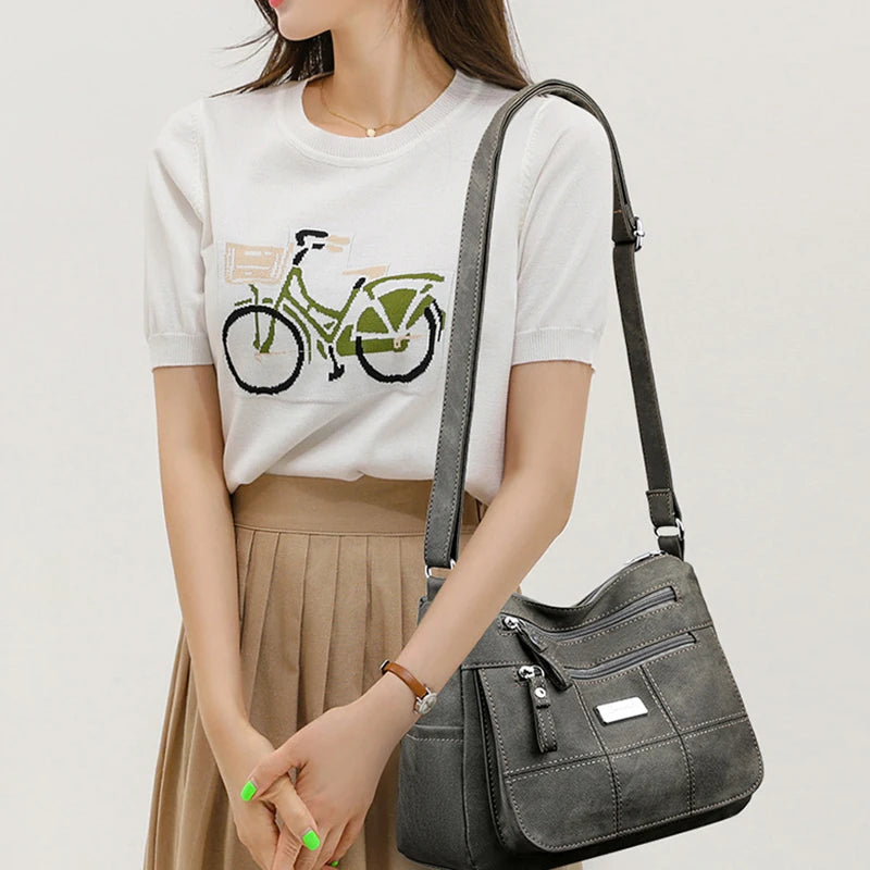 Woman holding a gray handbag wearing a white t-shirt with a bicycle graphic.