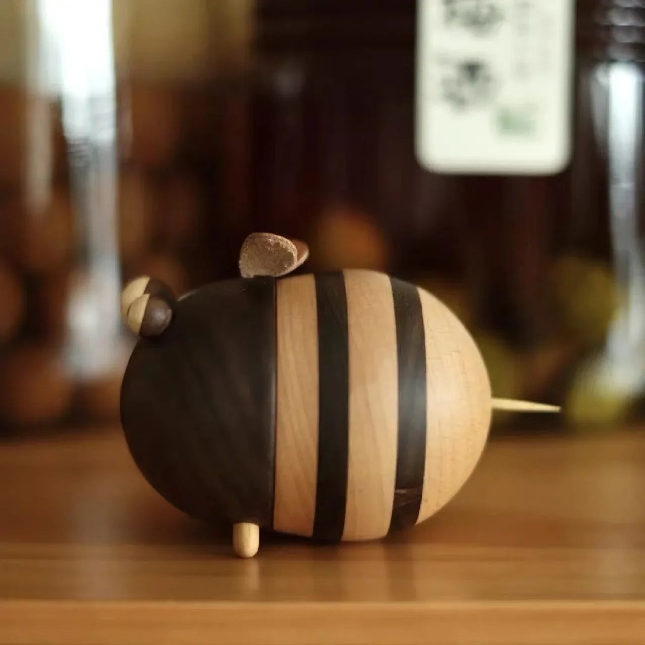 Two handcrafted wooden bee toothpick holders with striped natural wood finish displayed on a wooden tabletop as decorative kitchen accessories.