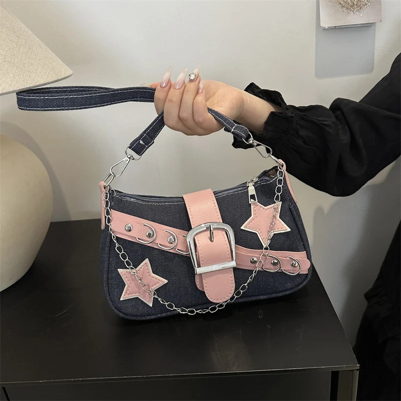 Handbag with star designs and a belt buckle held by a person on a dark surface.