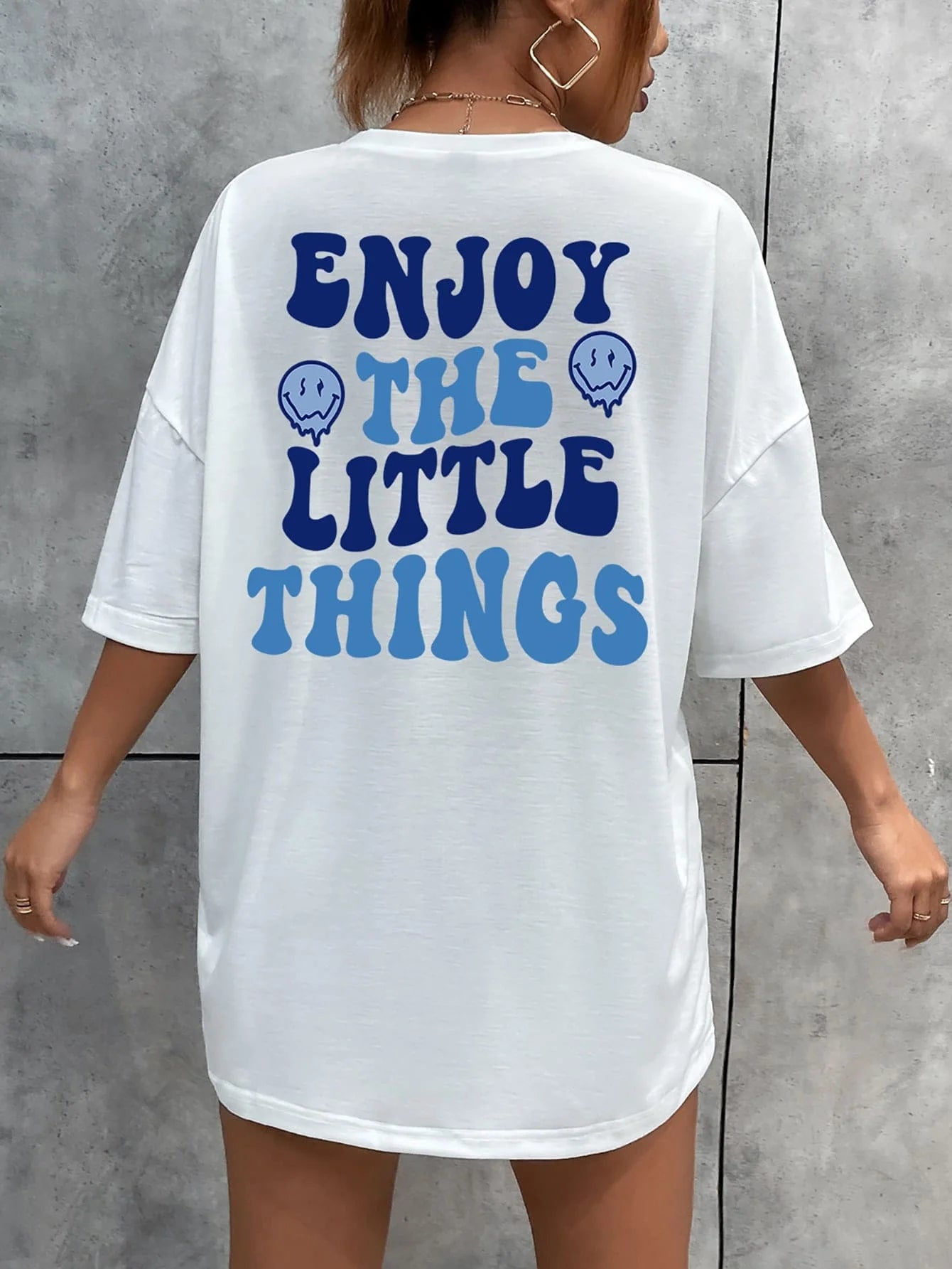 White t-shirt with blue text 'ENJOY THE LITTLE THINGS' on a gray background