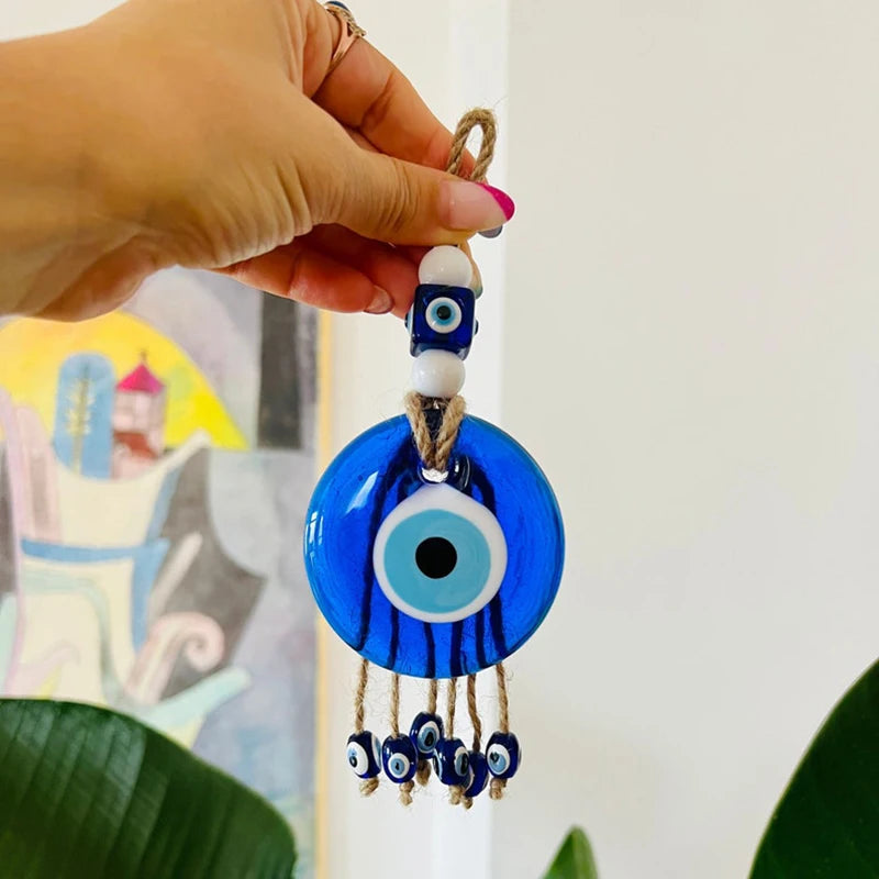 Hand holding a blue evil eye decorative item with a blurred background