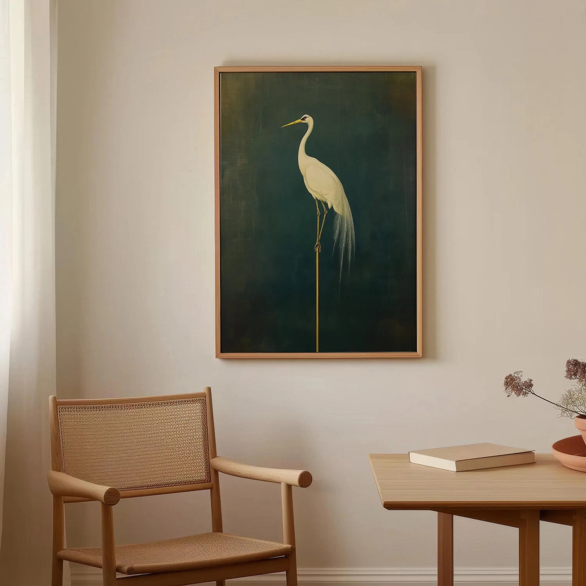 Framed artwork of a crane on a wall above a wooden chair and table.