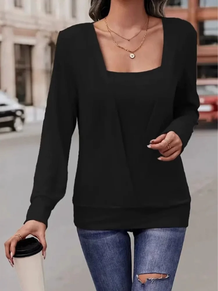 Person wearing a black long-sleeve top and blue jeans on a city street.