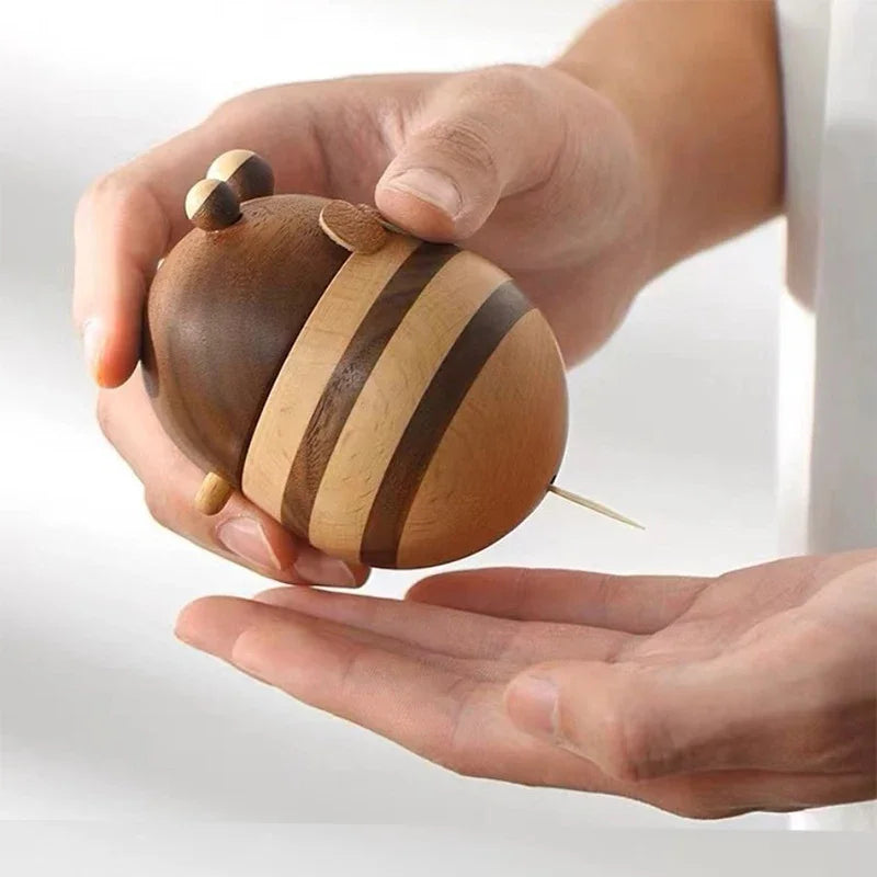 Two handcrafted wooden bee toothpick holders with striped natural wood finish displayed on a wooden tabletop as decorative kitchen accessories.