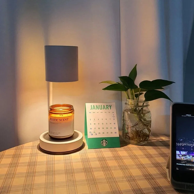 Candle, lamp, plant, and smartphone on a table with a calendar indicating January.