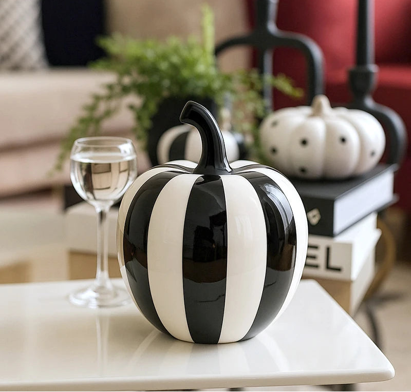 Black and white striped apple decoration on a table with a blurred living room background.