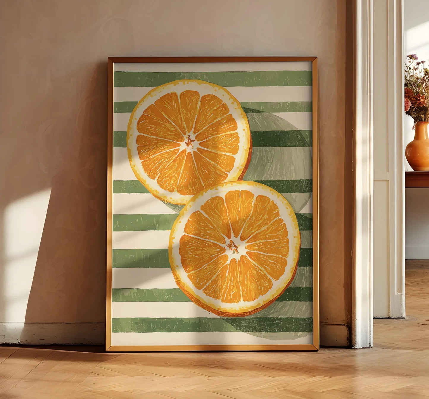 Framed artwork of two orange slices on a striped background in a room with a wooden floor.