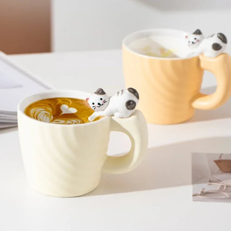 Two mugs with cat-shaped handles on a white surface