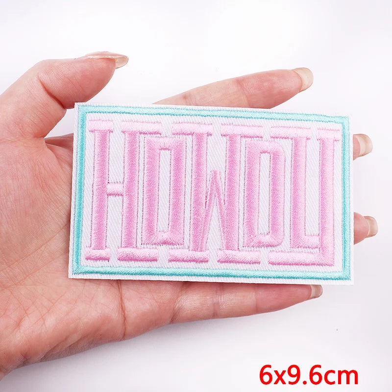 Hand holding a patch with 'HOWDY' text on a white background