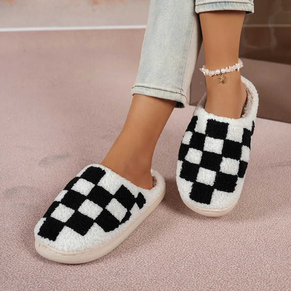 Checkered slippers worn with light jeans on a pink surface