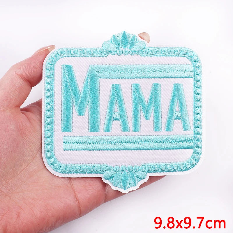 Turquoise 'MAMA' patch held in a hand with a white background