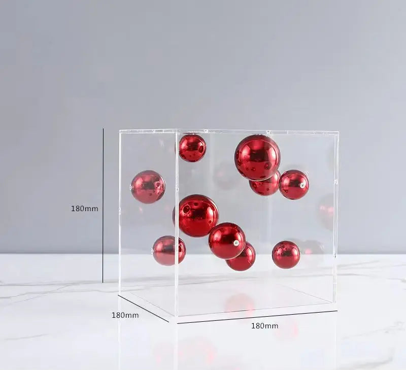 Clear acrylic display box with red spherical objects on a gray background