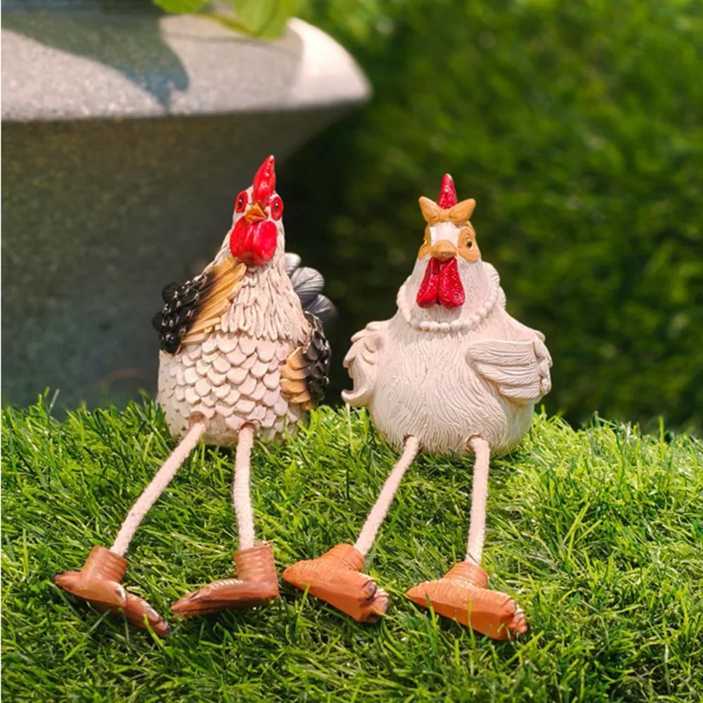 Two decorative chicken figurines on grass with a blurred background