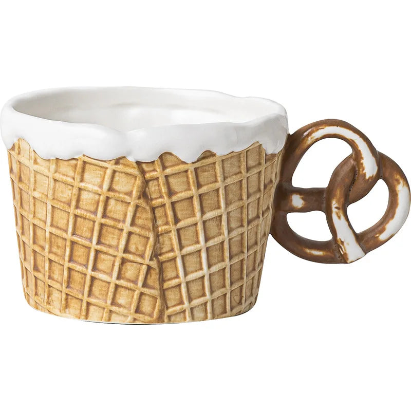 Ceramic mug designed like a waffle cone with a pretzel handle on a white background