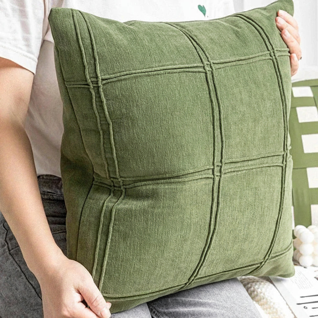 Green pillow held by a person with a blurred background