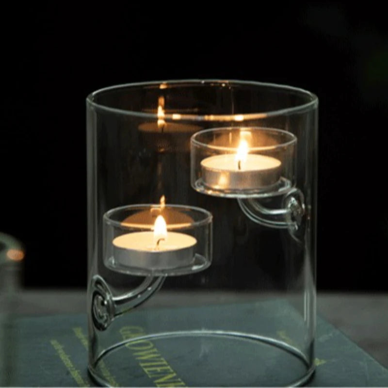 Clear glass candle holder with three lit candles on a dark background