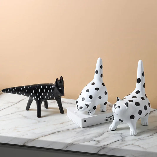 Three ceramic cat and fox figurines with black and white polka dot patterns on a marble surface