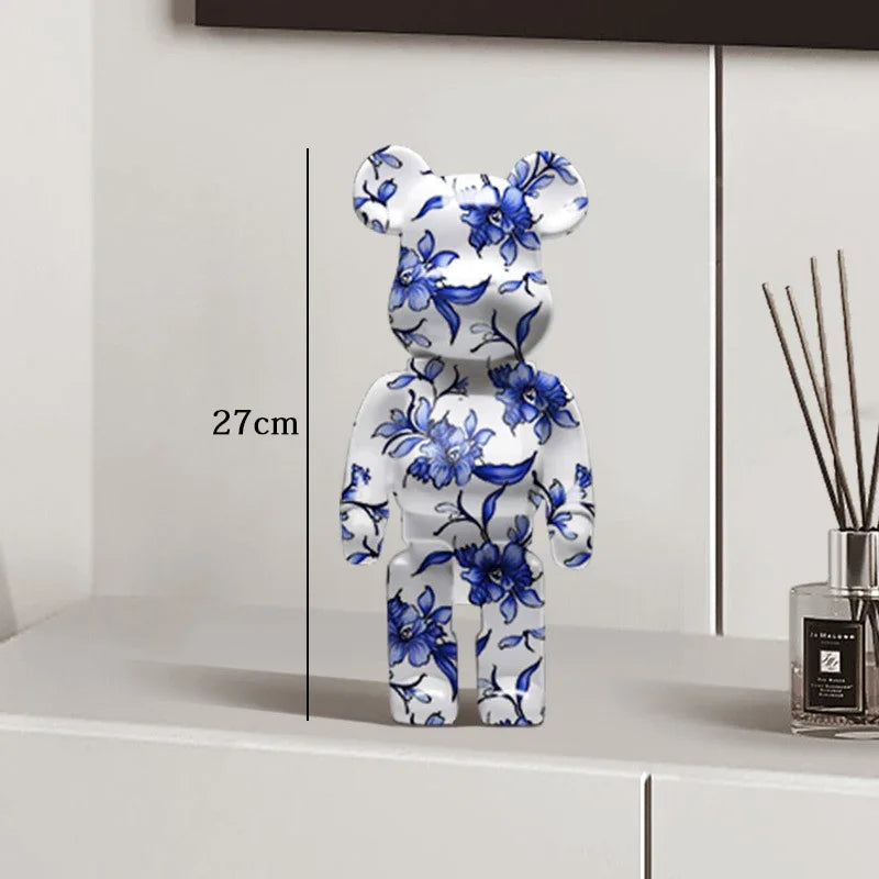 Decorative bear figure with blue floral patterns on a white surface, next to a diffuser.