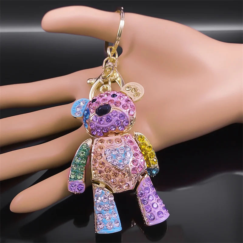 Colorful teddy bear keychain held by a hand on a dark background