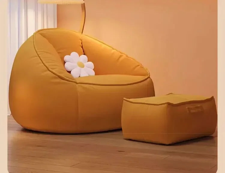 Yellow bean bag chair with a matching ottoman and white flower pillow on a wooden floor.