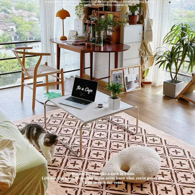 Modern living room with a laptop on a coffee table, a cat on the floor, and a view of the outdoors.