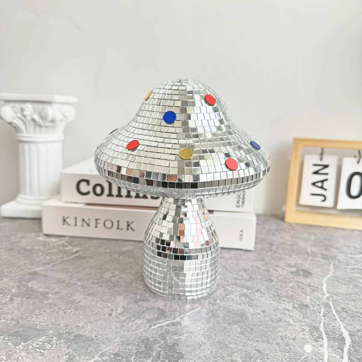 Decorative disco mushroom ornament with colorful dots on a marble surface.