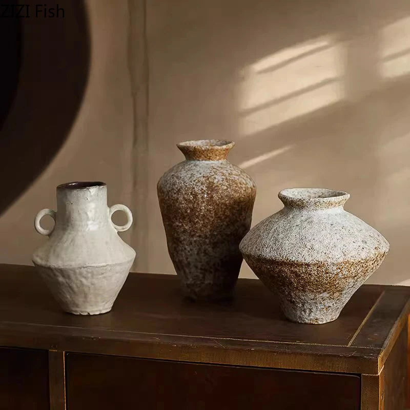 Three rustic Wabi-sabi ceramic vases on a wooden surface with a neutral background