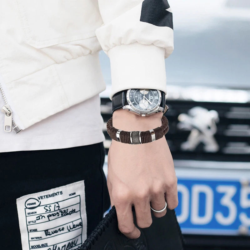 Person wearing a watch and bracelet with a blurred car and 'Vetements' label in the background