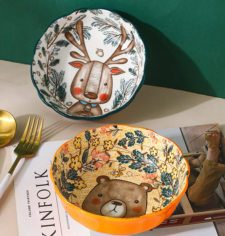 Two ceramic bowls with animal designs on a table with a magazine underneath.