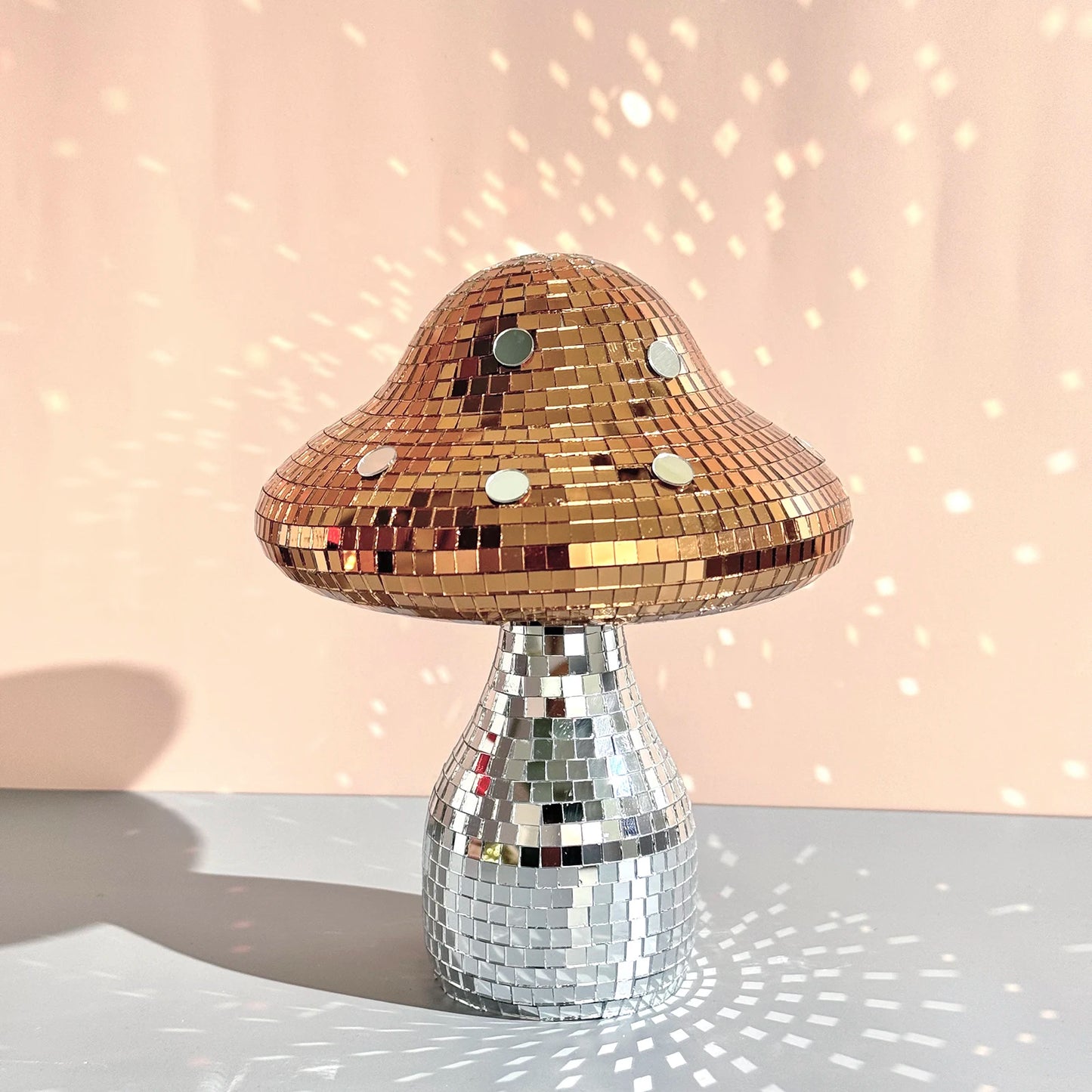Mushroom-shaped ornament on a reflective surface with a soft pink background