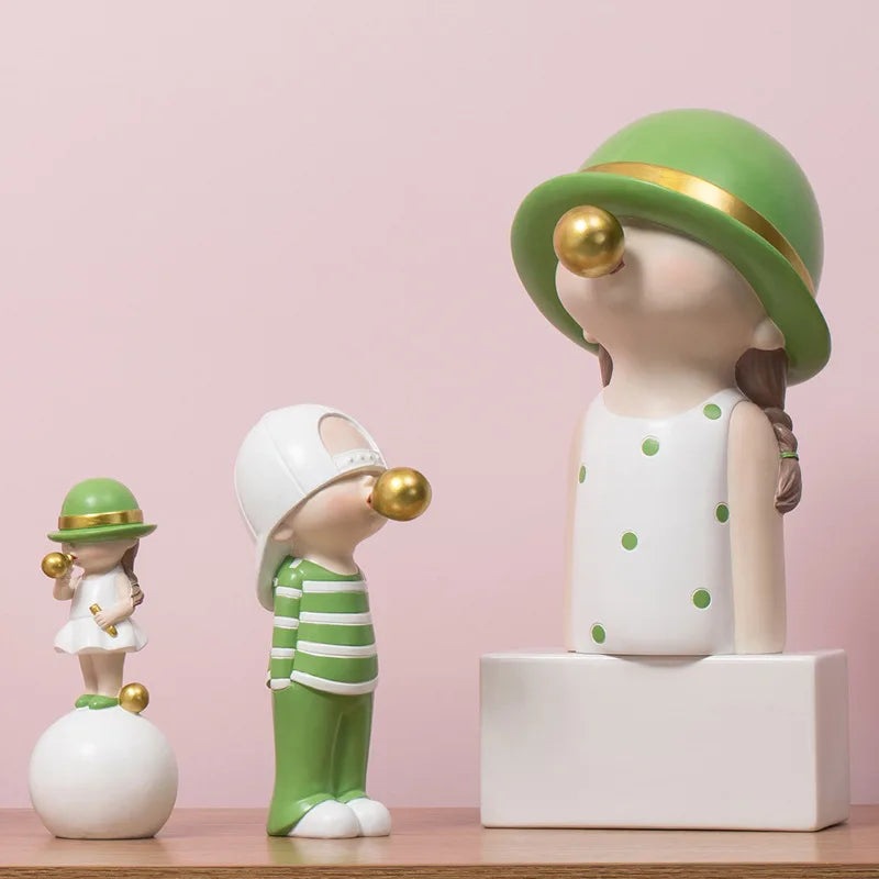 Three decorative figurines in green and white on a pink background blowing bubblegum