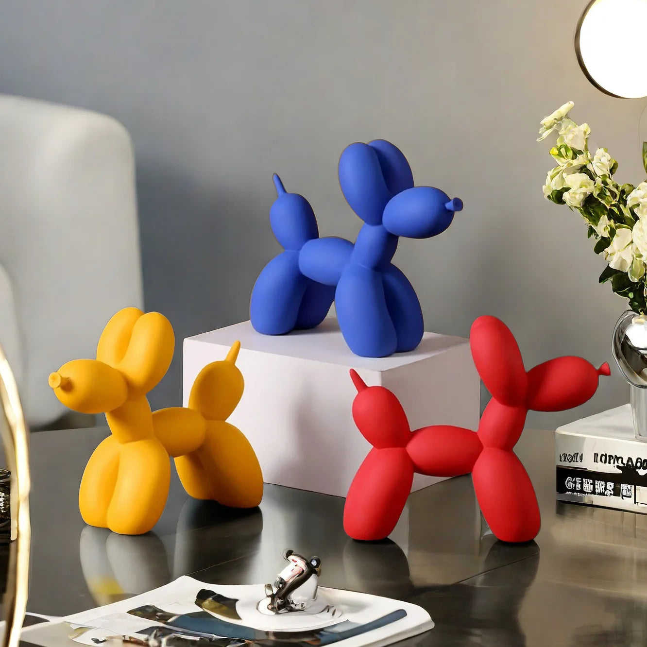 Modern balloon dog resin sculpture in blue, yellow and red displayed on a contemporary coffee table.