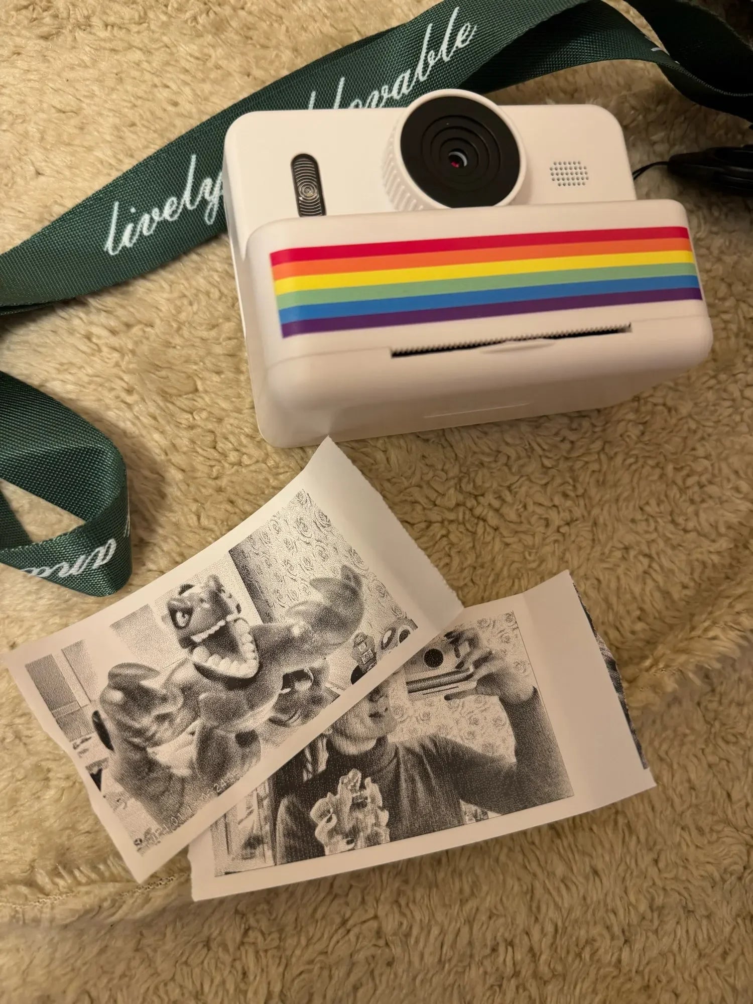 White camera with rainbow stripe and two black and white photos on a textured surface
