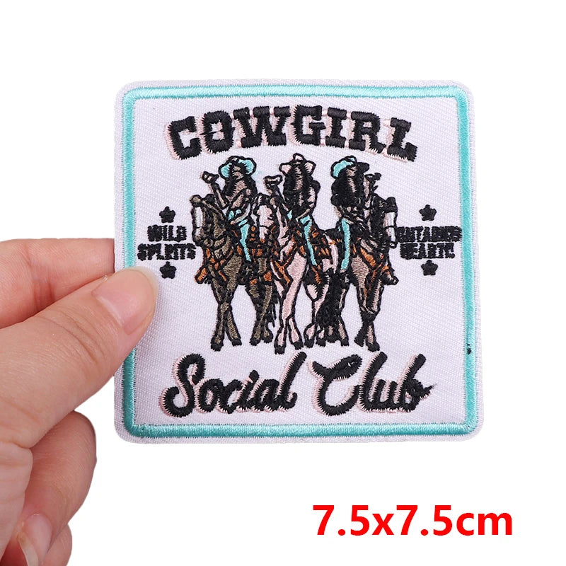 Patch with 'Cowgirl Social Club' design held by a hand, size 7.5x7.5cm.
