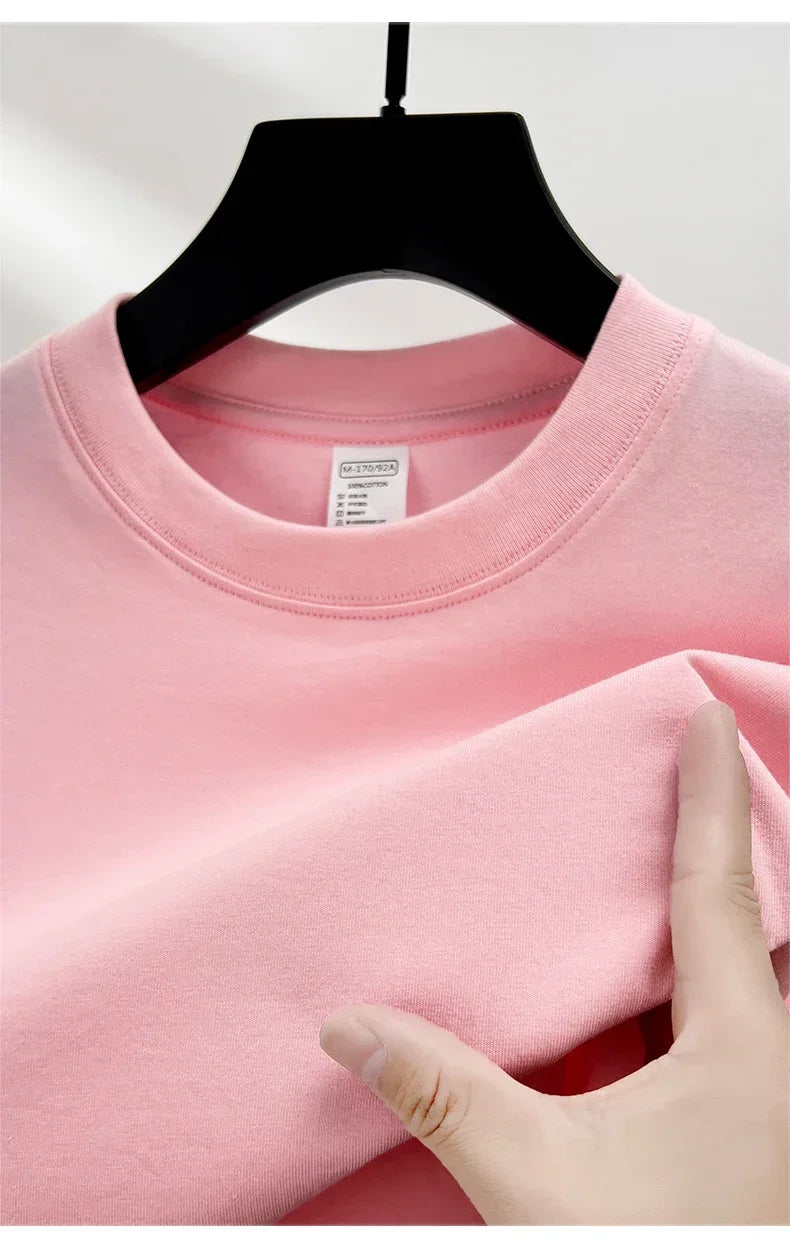 Pink t-shirt on a hanger with a hand touching the fabric