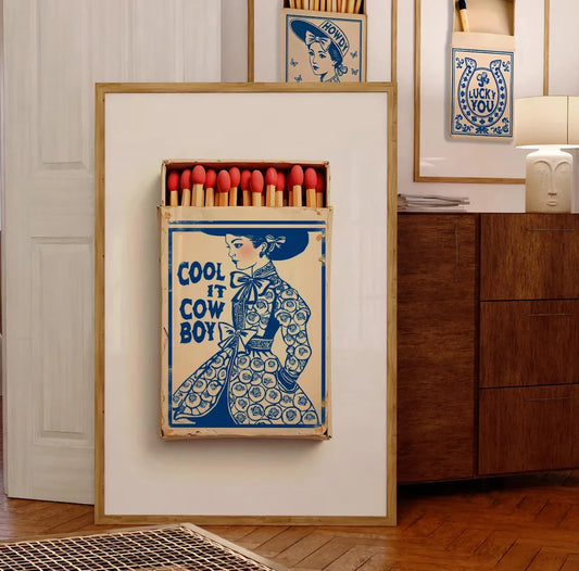 Decorative Poster matchbox with a graphic design of a cowgirl on a wall.