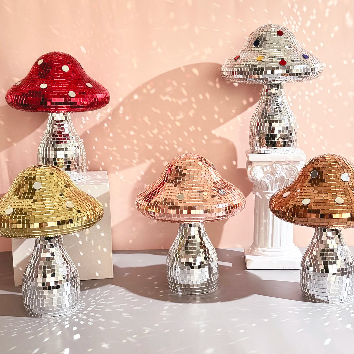 Set of disco mushroom ornaments with colorful bases on a light pink background