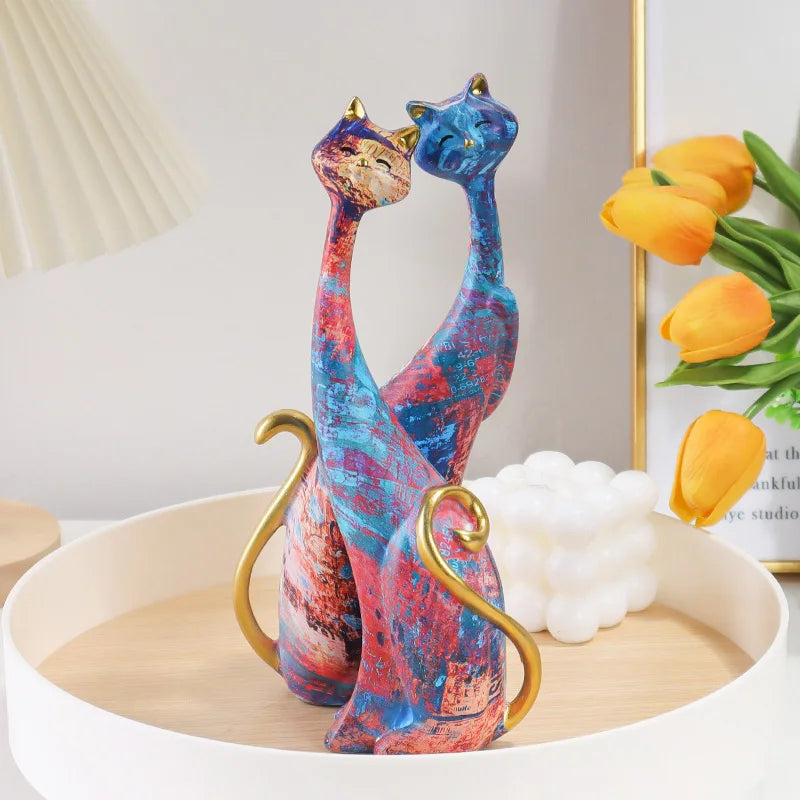 Pair of decorative resin cat sculptures with elongated modern silhouettes and artistic finishes, displayed as contemporary home decor on a tabletop.