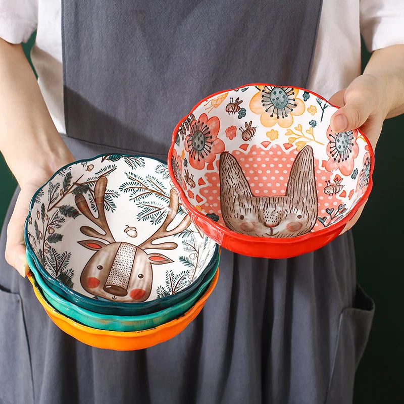 Person holding a stack of colorful bowls with animal designs.