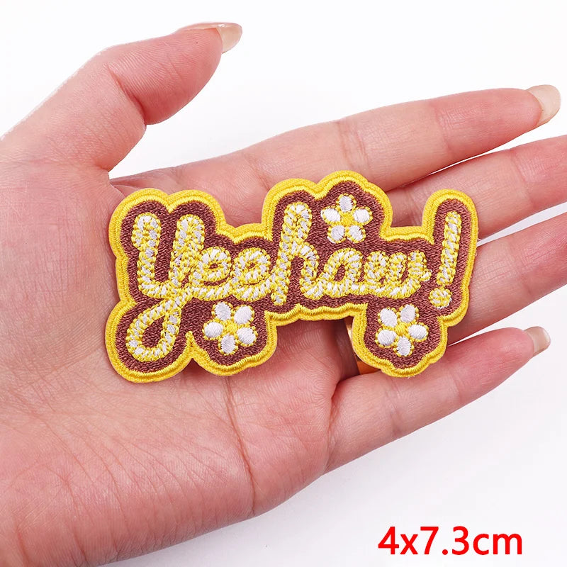 Decorative patch with 'Yeehaw!' text held in a hand on a white background