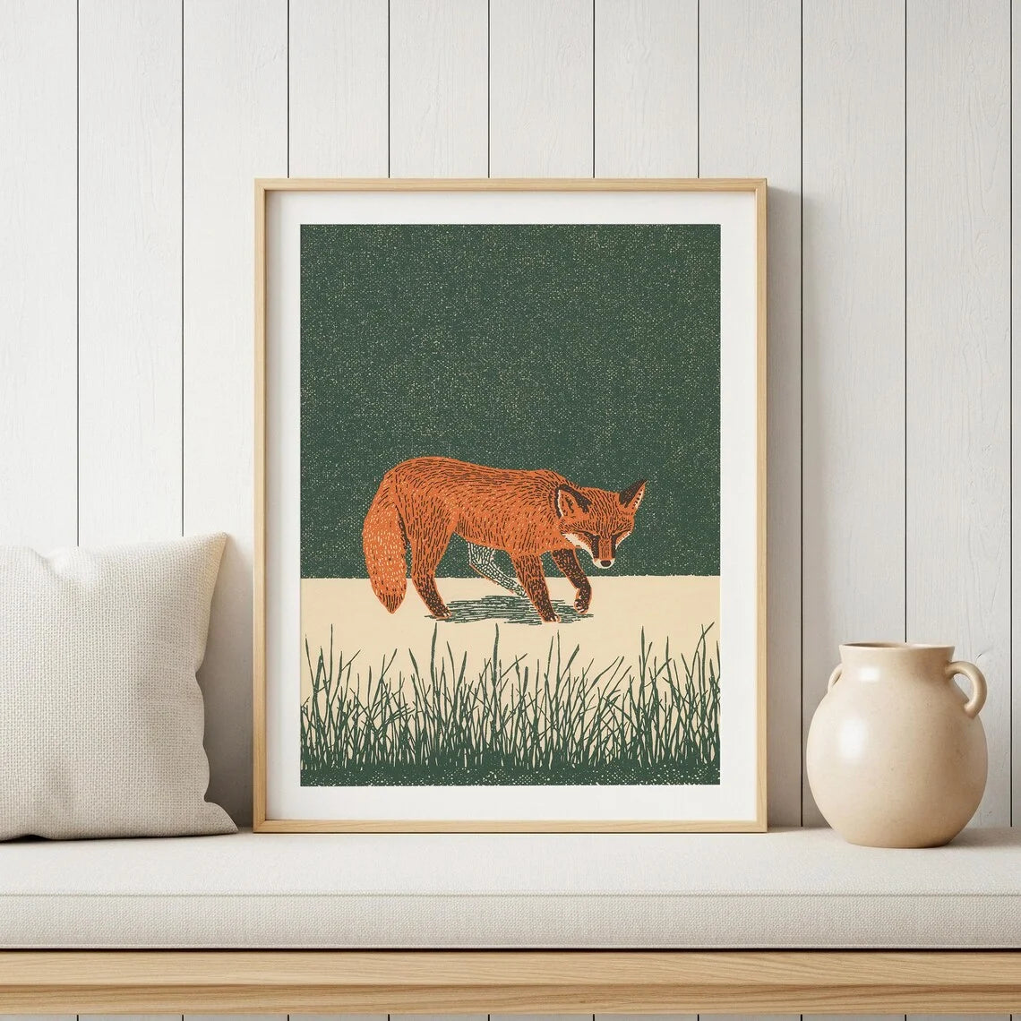 Minimalist Japanese-inspired fox art print showing an orange fox carrying a lantern through tall grass against a deep green background in a natural wood frame.