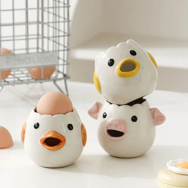 Three ceramic egg white separator shaped like a duck, chicken, and pig on a light surface.