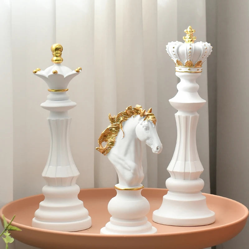 Decorative chess pieces with gold accents on a round pink surface against a light curtain background.