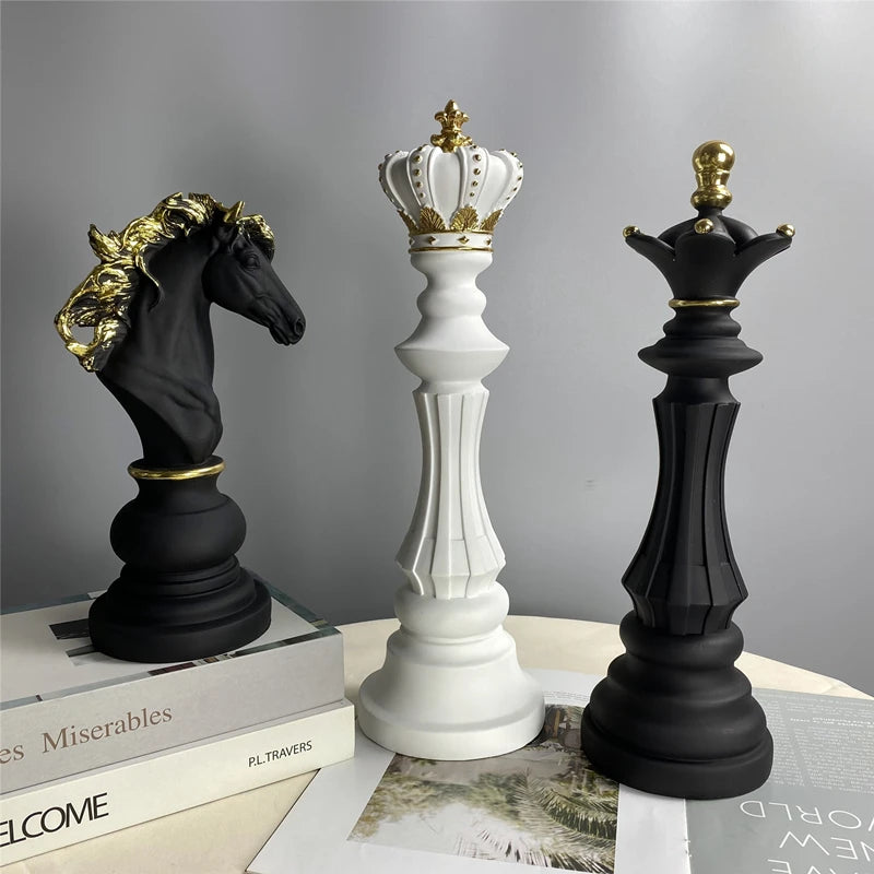 Decorative chess pieces with crowns on a surface with books and papers.