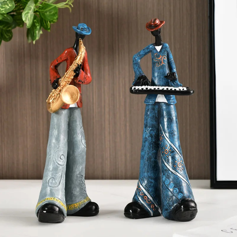 Two decorative figurines of musicians, one playing a saxophone and the other on a keyboard, against a neutral background.