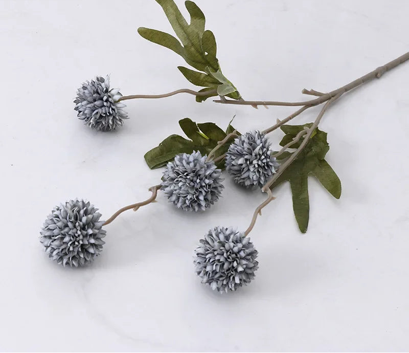 Decorative branch with gray spherical flowers and green leaves on a white background