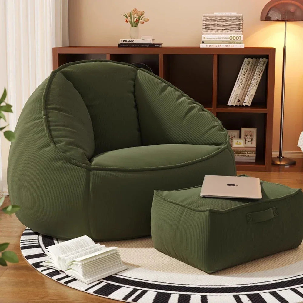 Green bean bag chair with ottoman in a cozy room setting.